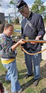 Supplied photo courtesy of the Cameron Art Museum/Alan Cradick. Dr. Malcolm Beech, U.S. Colored Troops re-enactor and USCT Living History Association president, helps a young student hold a replica Civil War era rifle during the 2012 Battle of Forks Road Civil War Weekend at the Cameron Art Museum.
