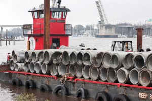 Staff photo by Allison Potter. A barge at Atlantic Coast Industrial, on the Cape Fear River, is loaded with pipes that will be dropped onto artificial reefs off Wrightsville’s coast.
