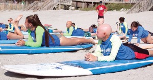 Staff photo by Emmy Errante. Sisters Elli and Adi Goldfrad learn how to pop up on a surfboard during Alopeciapalooza in Topsail Beach Friday, Aug. 14.