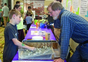 Cape Fear River Watch volunteer Roger Shew shows children how to create a miniature retrofitted dam like the one StriperFest raises money to build.