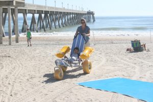 Shannon Bordeaux of Rocky Point, N.C. , and son Joren, 6, test a "Water Wheel" brand sand wheelchair Monday on Wrightsville Beach. Staff photo by Terry Lane.