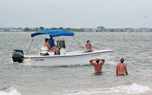 Lumina News file photo. A man pleads for a ride from a boater on Masonboro Island as Independence Day 2016 partying wraps up.